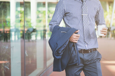 Midsection of businessman holding coffee cup