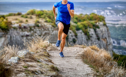 Runner athlete run mountain narrow trail along canyon