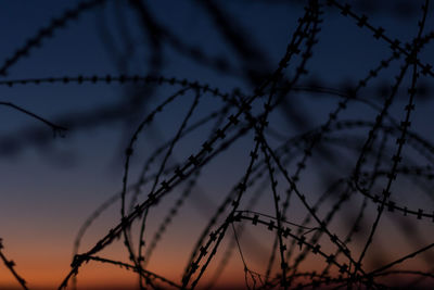 Low angle view of barbed wire fence against sky