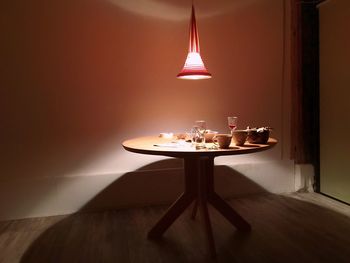 Illuminated pendant light above drinking glasses and cups served with food on table