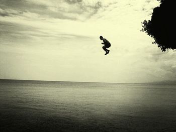 Silhouette of woman jumping in sea