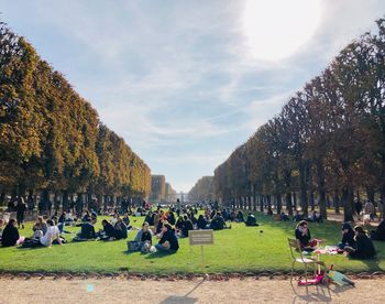 People relaxing on cemetery against sky