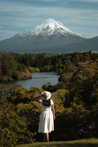 Rear view of woman on snowcapped mountain by lake