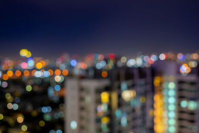 Defocused image of illuminated cityscape against sky at night