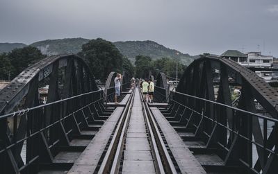 Footbridge over railroad tracks against sky