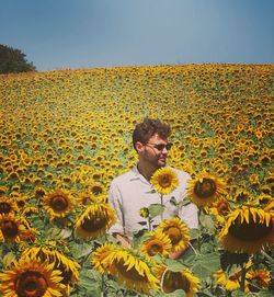 Woman on sunflower field against clear sky