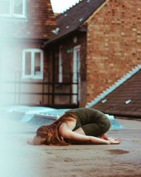 Woman lying down on building