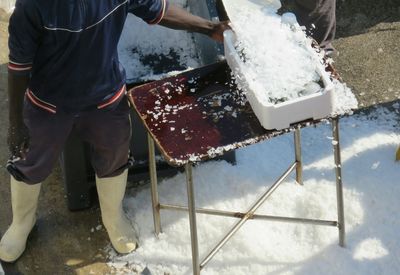 High angle view of fisherman covering fish with ice by machine at harbor