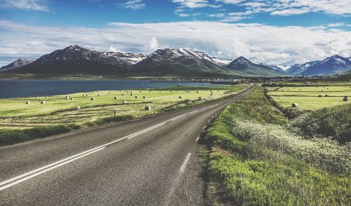 Country road on field against sky