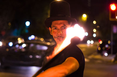 Portrait of man performing with fire in city at night