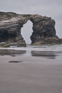 Rock formation on beach against sky