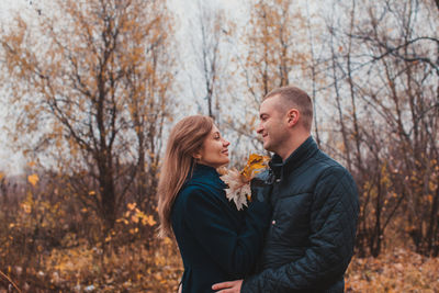 Young man and woman standing against trees