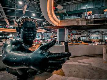 Close-up of statue against illuminated city