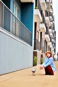 Woman crouching by animal representation on footpath