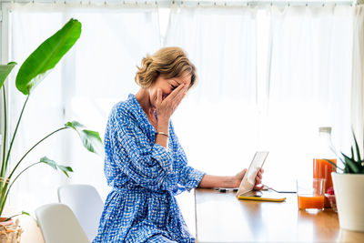 Young woman using digital tablet while sitting at home