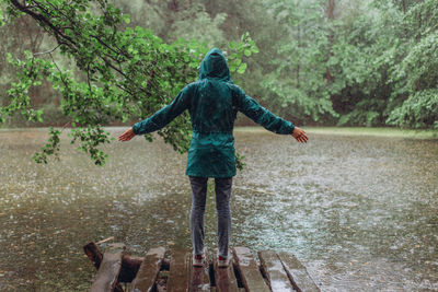 Rear view of woman standing by river in forest