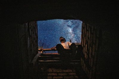 Young woman sitting on staircase at night