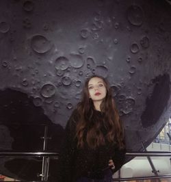 Portrait of beautiful woman standing against moon structure