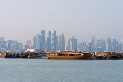 Sea by modern buildings against sky in city