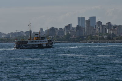 Boat sailing on sea against buildings in city