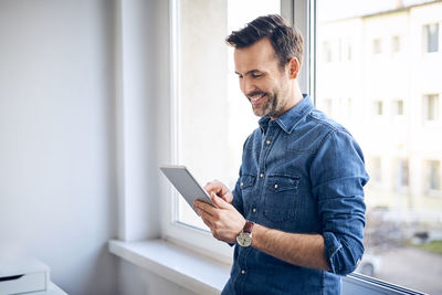 Smiling man using tablet at the window