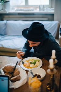 High angle view of businessman having food while sitting at table in creative office