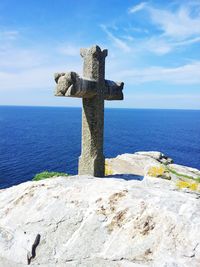 Cross on sea against sky