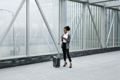 Woman holding umbrella while standing on mobile phone