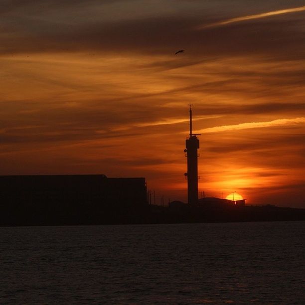 sunset, orange color, sky, built structure, architecture, building exterior, silhouette, waterfront, water, scenics, cloud - sky, tower, lighthouse, sea, beauty in nature, tranquility, tranquil scene, nature, communications tower, idyllic