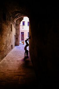 Young woman doing handstand in alley amidst buildings