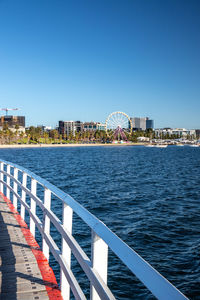 View of amusement park by sea against clear sky