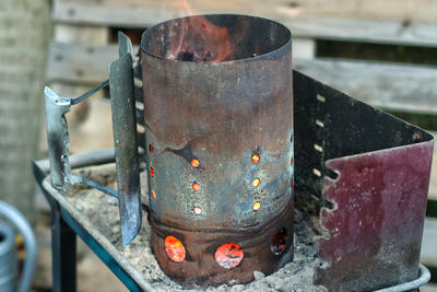 Close-up of rusty chimney starter on barbecue grill 