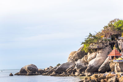 Cliff by sea against sky