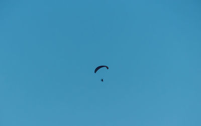 Low angle view of person paragliding against clear blue sky