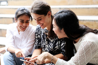 Women discussing over mobile phone while sitting on staircase