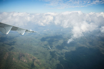 Aerial view of airplane flying over landscape against sky