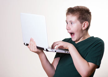 Low angle view of boy using mobile phone against white background