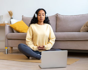 Portrait of young woman using laptop while sitting on sofa at home