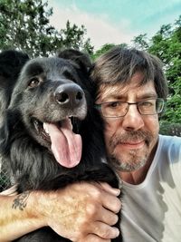 Portrait of senior man with dog against sky