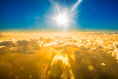 Airplane view of beautiful landscape with gold colored clouds, ocean and bright sunset shining sun