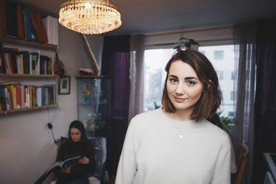 Portrait of young woman with female friend sittings in college dorm room