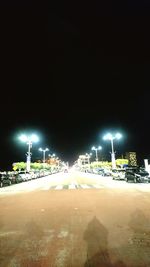 Illuminated city street against sky at night