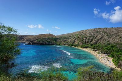 Scenic view of sea and mountains against blue sky