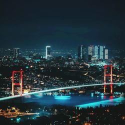 Illuminated modern buildings in city against sky at night