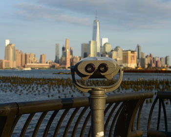 Close-up of coin-operated binoculars with buildings in backgrounds