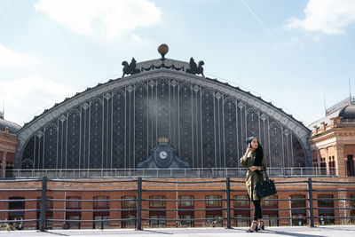 Rear view of man standing by railing against sky