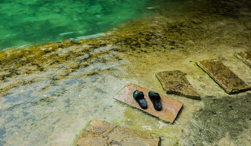 High angle view of slippers on stepping stones at lakeshore