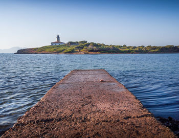 Lighthouse by sea against clear sky