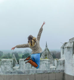 Woman jumping against old buildings in city