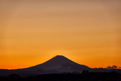 Scenic view of silhouette mountains against orange sky